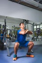 Sport, bodybuilding, lifestyle and people concept - young man with barbell doing squats in gym