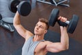 Sport, bodybuilding, training and people concept - young man with dumbbell flexing muscles. men working with dumbbells his body at