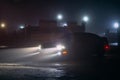 Sport car in the shadows with glowing lights in low light at foggy night, or silhouette of sport car dark background