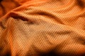 Sport clothing fabric texture background. Top view of orange polyester nylon cloth textile surface. Colored basketball shirt with Royalty Free Stock Photo