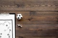 Sport coach concept. Pad with tactic plan of the match near whistle and football ball on wooden background top view copy Royalty Free Stock Photo