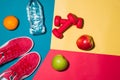 Sport concept. Fitness equipment. Sneakers, water, apple, dumbbell on colorful background. Royalty Free Stock Photo