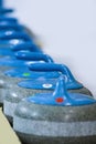 Sport Concepts. Closeup of Curling Blue Handle Stones on Ice