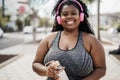 Sport curvy black woman listening music with headphones - Focus on face