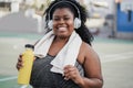 Sport curvy black woman listening music with headphones - Focus on face