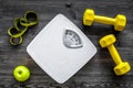 Sport and diet for losing weight. Bathroom scale, apple and dumbbell on wooden background top view Royalty Free Stock Photo