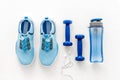 Sport equipment. Sneakers, dumbbells and water on white table top view flat-lay