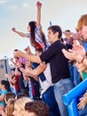 Sport fans hands up and singing on tribunes