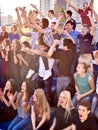 Sport fans hands up and singing on tribunes.