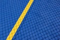 Sport field court background. Blue rubberized and granulated ground surface with yellow lines and tennis net shadow on Royalty Free Stock Photo