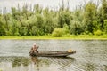 A sport fisherman rides around the pond in a wooden boat