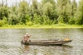 A sport fisherman rides around the pond in a wooden boat