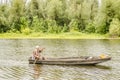 A sport fisherman rides around the pond in a wooden boat