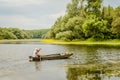 A sport fisherman rides around the pond in a wooden boat