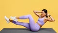 Sport and fitness concept. Young black woman doing bicycle crunch abs exercise, training on mat on yellow background