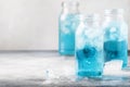 Sport and fitness drink concept, cold isotonic blue water in bottles, gray table background, selective focus Royalty Free Stock Photo