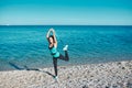 Sport and fitness idea. Healthy lifestyle concept. Girl stretching leg using rubber band. Coastline and calm ocean view