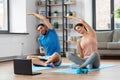Happy couple with laptop exercising at home