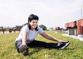 Smiling senior woman warming up stretching sitting on the grass in the park Royalty Free Stock Photo