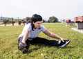Smiling senior woman warming up stretching sitting on the grass in the park Royalty Free Stock Photo