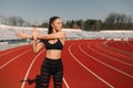 Sport fitness woman stretching on the stadium.Sport blond girl stretching arms in sport running arena with many tracks. Royalty Free Stock Photo