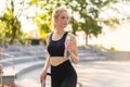Sport and Fitness. Young Caucasian Woman Dressed Sportswear Drink Water Plastic Bottle Standing Outdoor Summer Park Sunlight Royalty Free Stock Photo