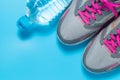 Sport flat lay pink shoes and bottle of water on blue background with copyspace for your text. Concept healthy lifestyle and diet Royalty Free Stock Photo