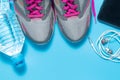 Sport flat lay pink shoes with bottle of water, phone, earphones on blue background with copyspace. Concept healthy lifestyle Royalty Free Stock Photo