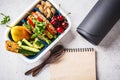 Sport food concept. Lunch box with heathy food, notebook and mat on a gray background