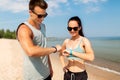 Happy couple with fitness trackers on summer beach