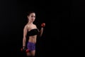 Sport girl holding a dumbbell on black background.