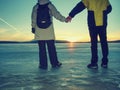 Sport girl holds boy hand. People in winter clothes running away to horizon of icy sea