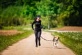 Sport girl is running with a dog Beagle on the rural road towadrds camera