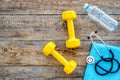 Sport and health. Fitness. Dumbbells and stethoscope on wooden background top view copyspace