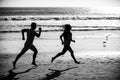 Sport and healthy lifestyle, friends jogging at sunset on the beach. Silhouette couple running on beach. Royalty Free Stock Photo