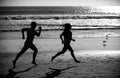 Sport and healthy lifestyle, friends jogging at sunset on the beach. Silhouette couple running on beach. Royalty Free Stock Photo