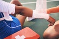 Sport injury, bandage and first aid with wrist pain and help, health and medic, accident and people on netball court