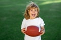 Sport kid. Kid boy having fun and playing american football on green grass park. Royalty Free Stock Photo