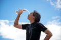 Sport man athletes pour water on their faces and holding a water bottle drinking water after exercise,back ground blue sky.