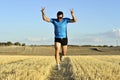 Sport man running outdoors on straw field doing victory sign in frontal perspective Royalty Free Stock Photo