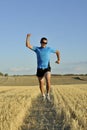 Sport man running outdoors on straw field doing victory sign in frontal perspective Royalty Free Stock Photo