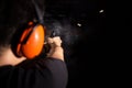 Sport man shooting pistol gun with smoke and fire bullet on black background in shootingrange