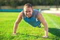 Sport man stretching at the park, doing push-ups on grass a sunny day. Fitness concepts Royalty Free Stock Photo