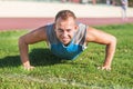 Sport man stretching at the park, doing push-ups on grass a sunny day. Fitness concepts. Royalty Free Stock Photo