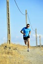 Sport man with sun glasses running on countryside track with power line poles