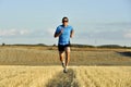 Sport man with sunglasses running outdoors on straw field ground in frontal perspective Royalty Free Stock Photo