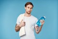 sport man with tattoos on his arms water bottle energy blue background