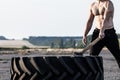 Sport muscular man hitting wheel tire with hammer sledge in the gym. Sports training Royalty Free Stock Photo