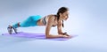Muscular woman on a plank position use fitness gum. Muscular and strong girl exercising.