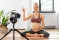 Pregnant woman or yoga blogger with camera at home Royalty Free Stock Photo